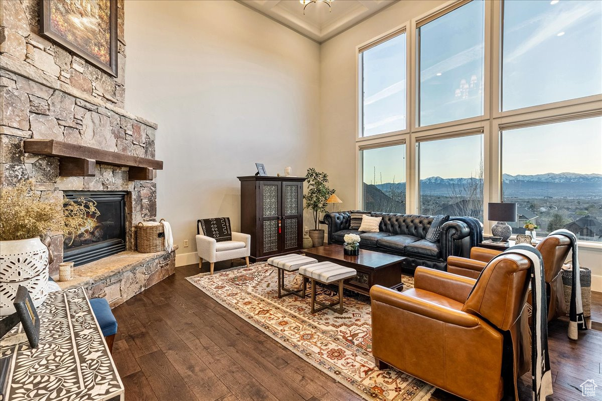 Living room featuring a fireplace, engineered hardwood flooring, a mountain view, and a towering ceiling