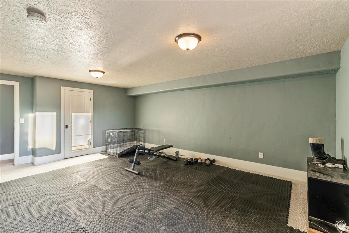 Exercise room with carpet and a textured ceiling