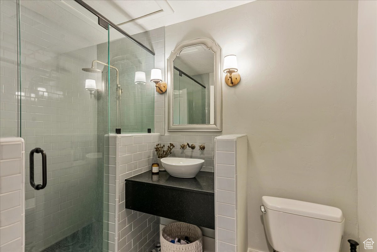 Bathroom featuring vanity, a shower with door, tasteful backsplash, and toilet