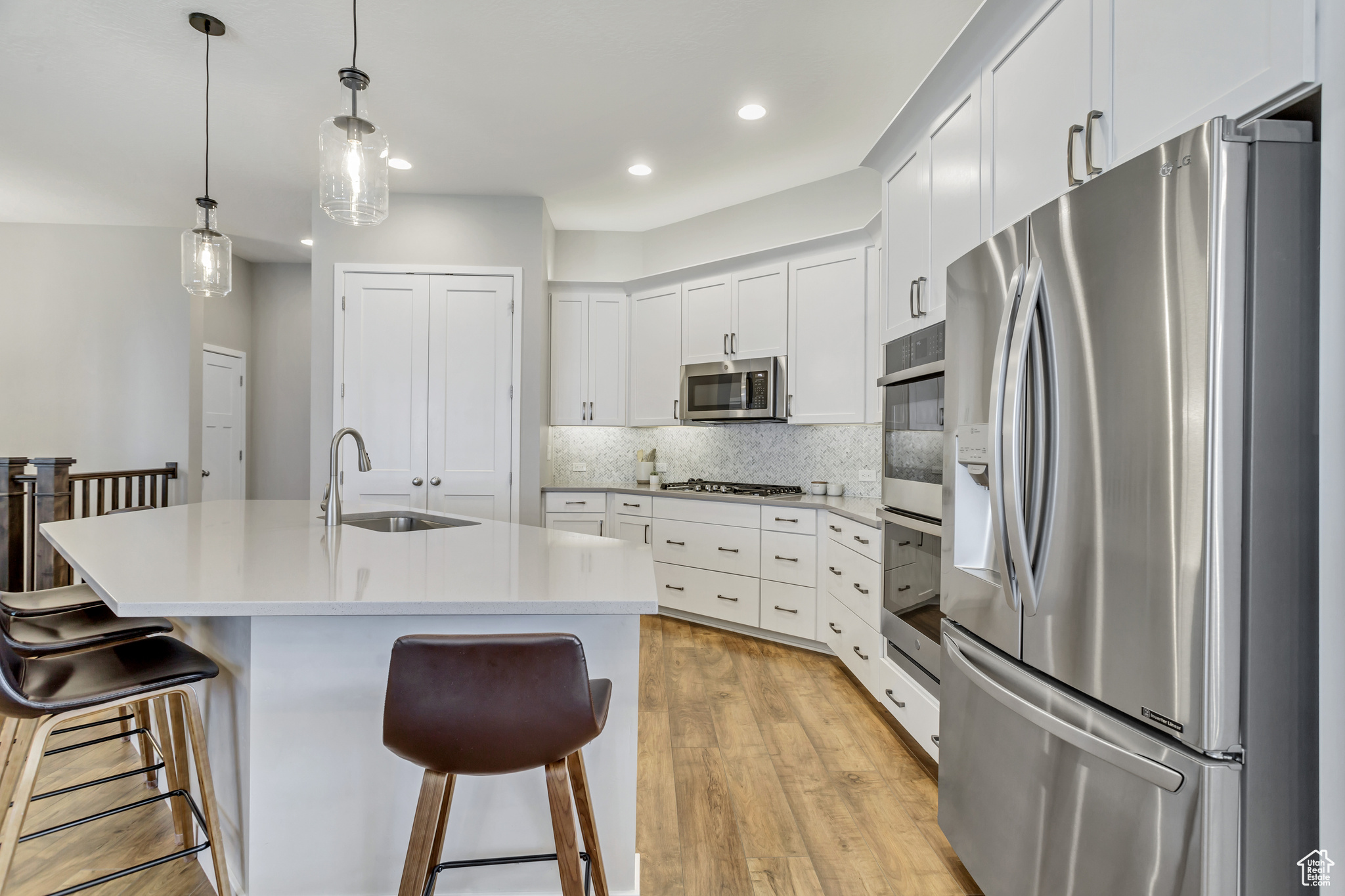 Kitchen featuring pendant lighting, a breakfast bar, stainless steel appliances, sink, and light hardwood / wood-style flooring