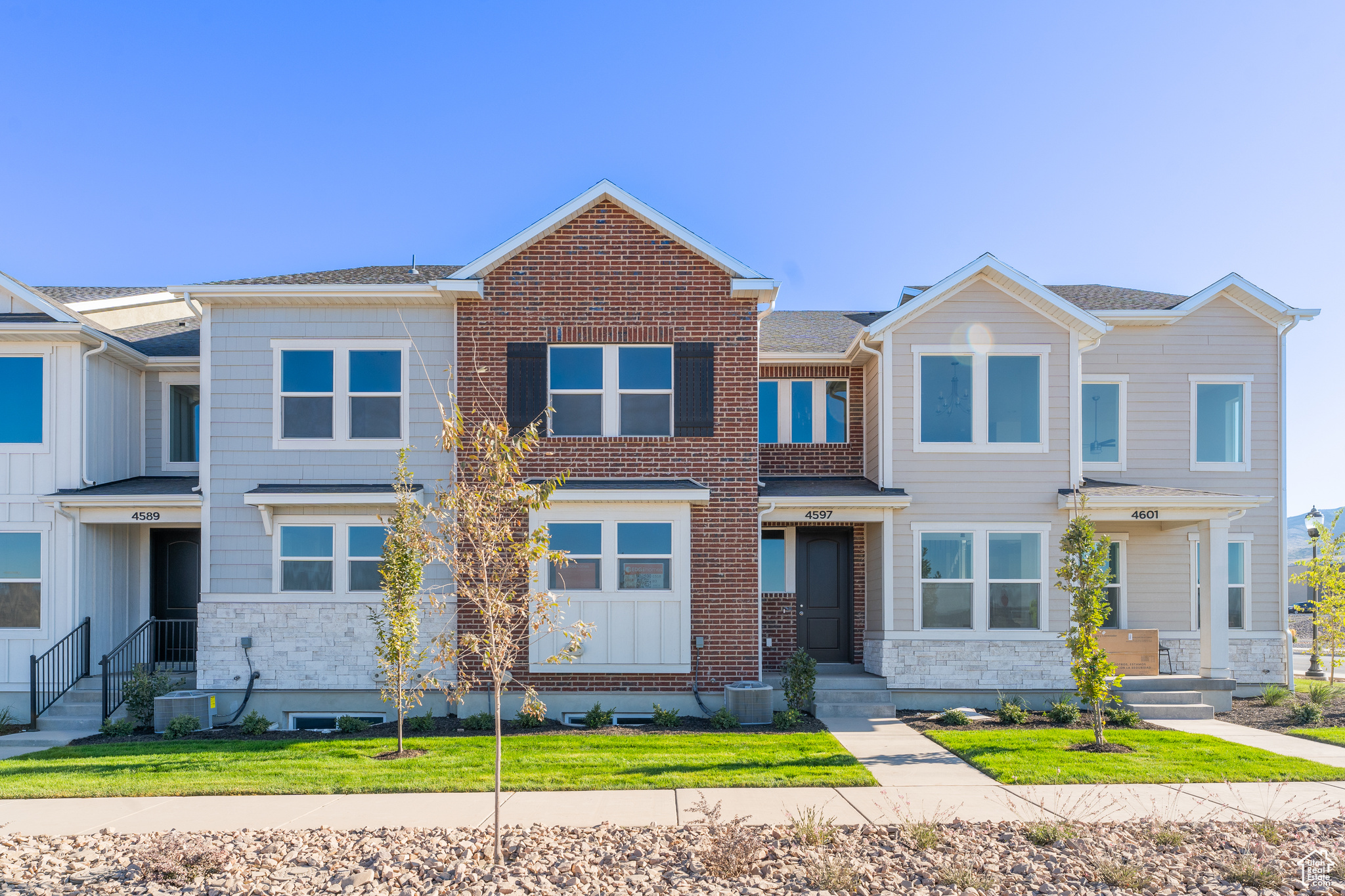 View of front of home with central AC unit and a front lawn