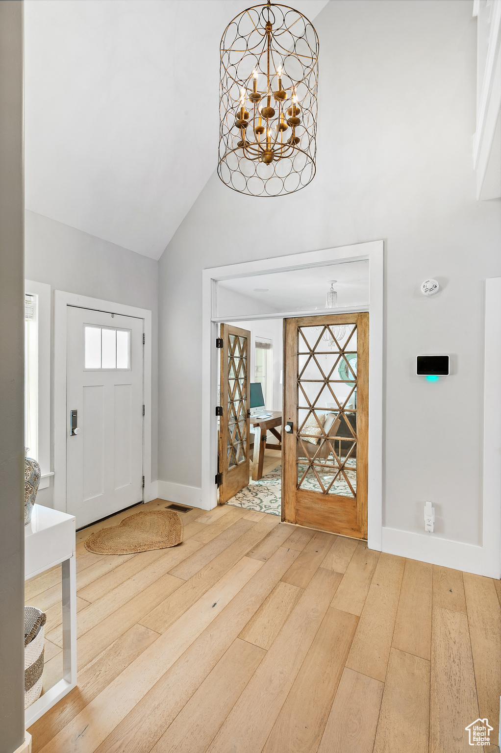 Entryway with an inviting chandelier, vaulted ceiling, and light hardwood flooring