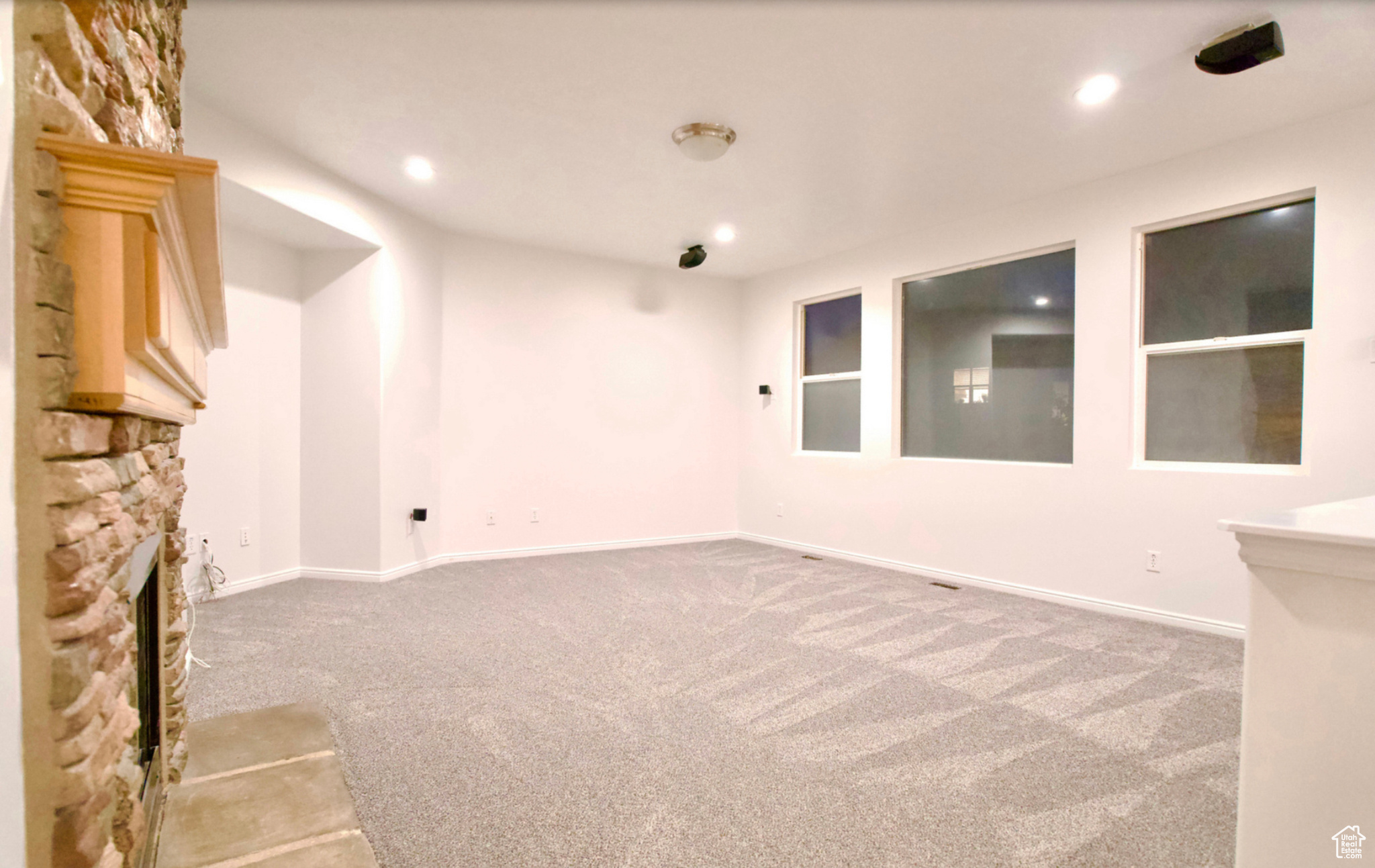 Interior space with light colored carpet and a stone fireplace