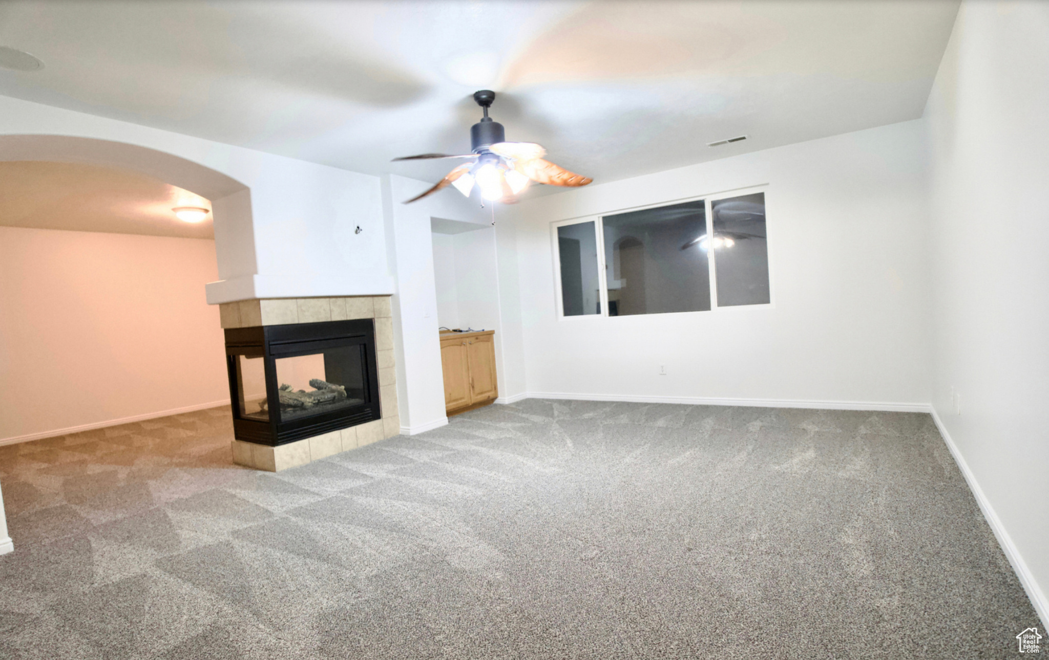 Unfurnished living room with ceiling fan, light carpet, and a fireplace