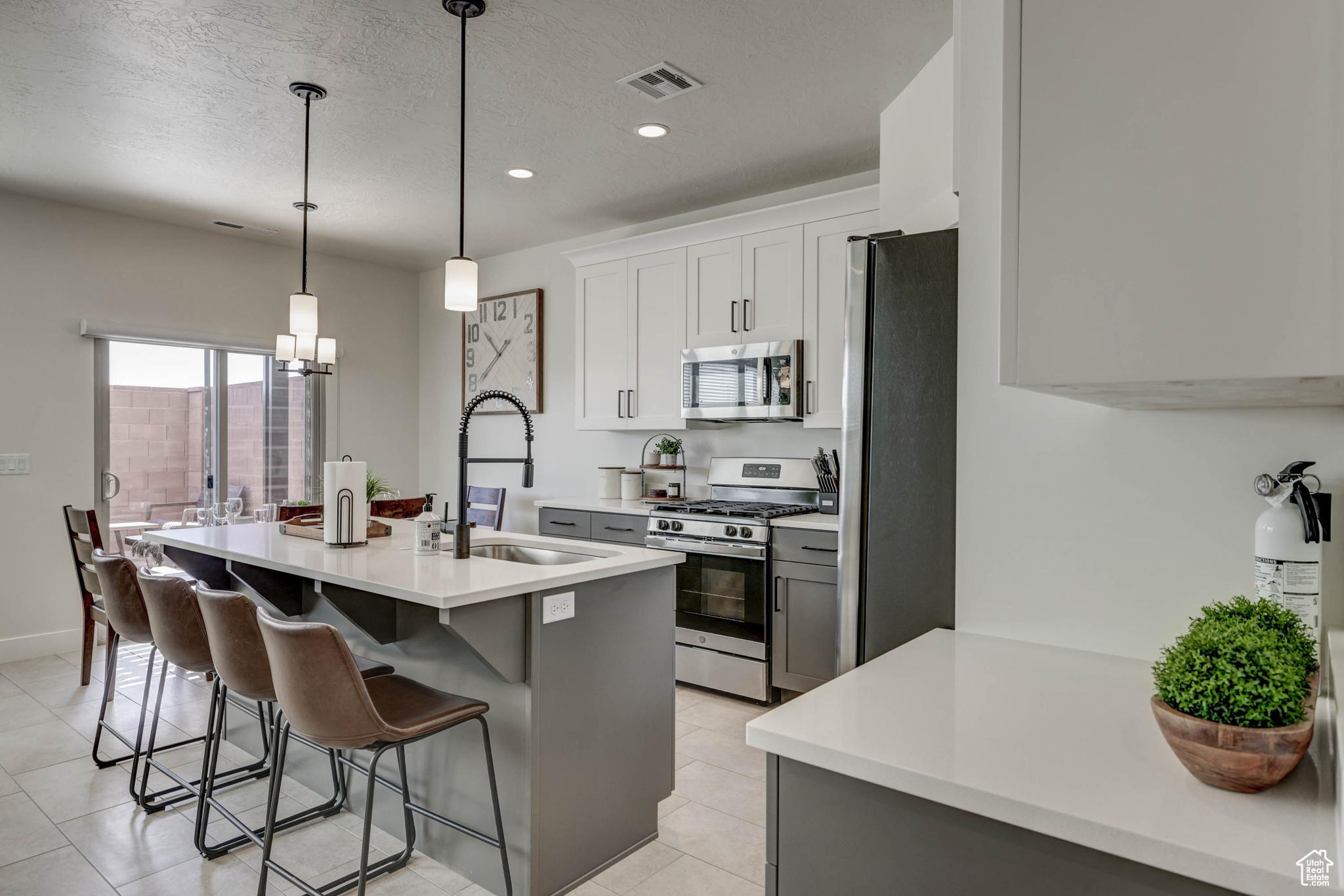 Kitchen with an inviting chandelier, light tile flooring, sink, and stainless steel appliances