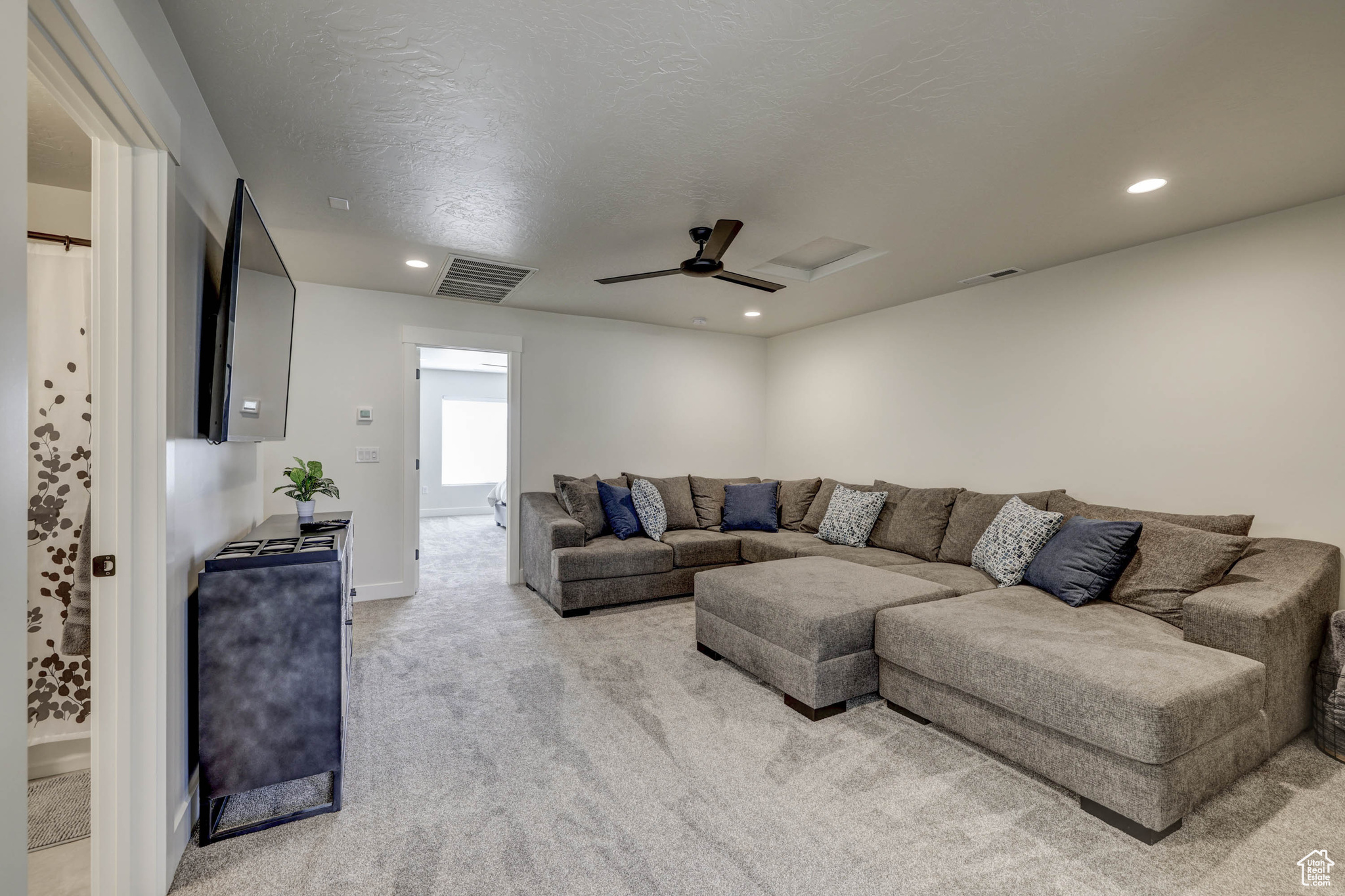 Carpeted living room featuring ceiling fan