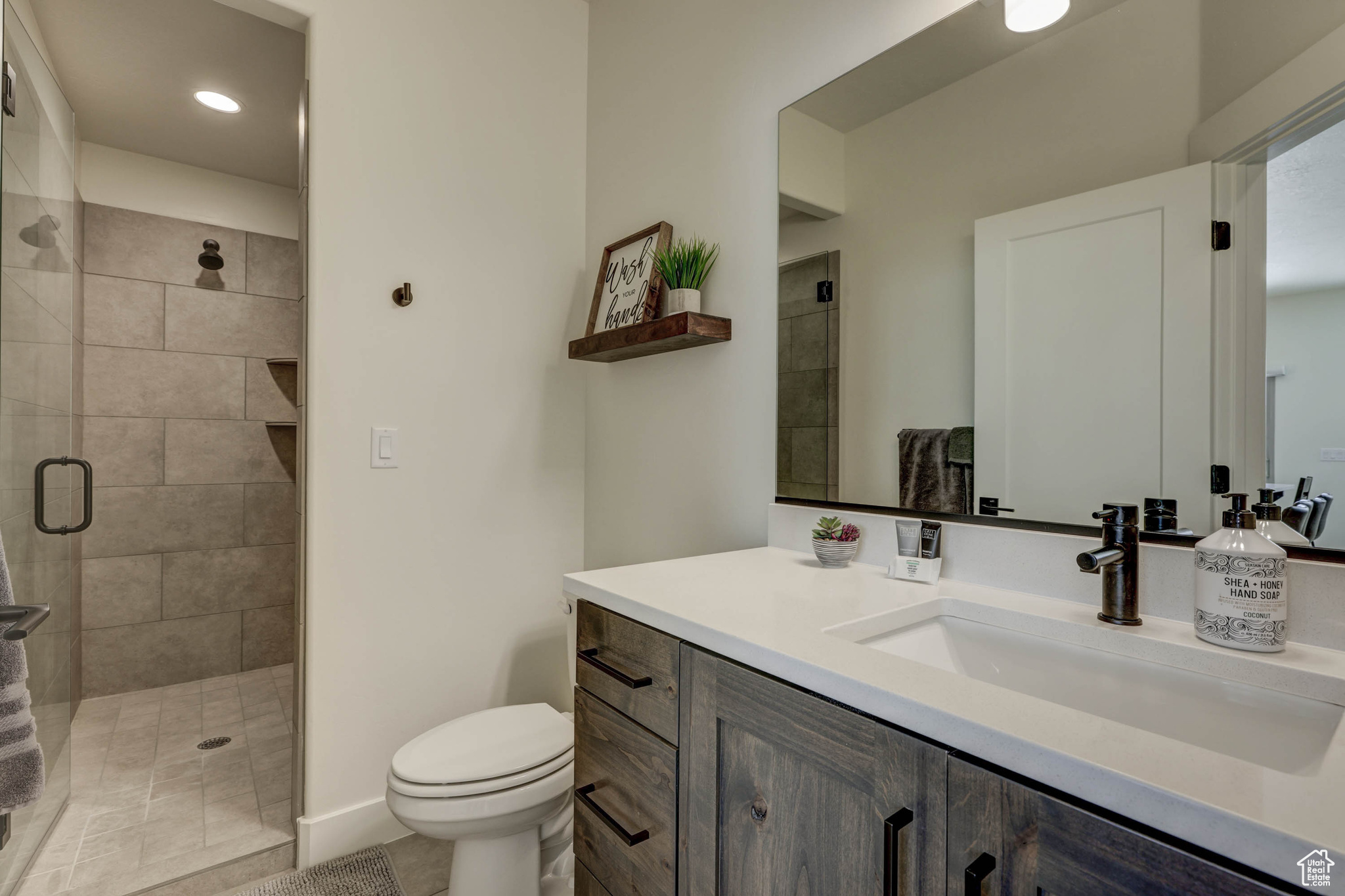 Bathroom with toilet, tile flooring, walk in shower, and vanity