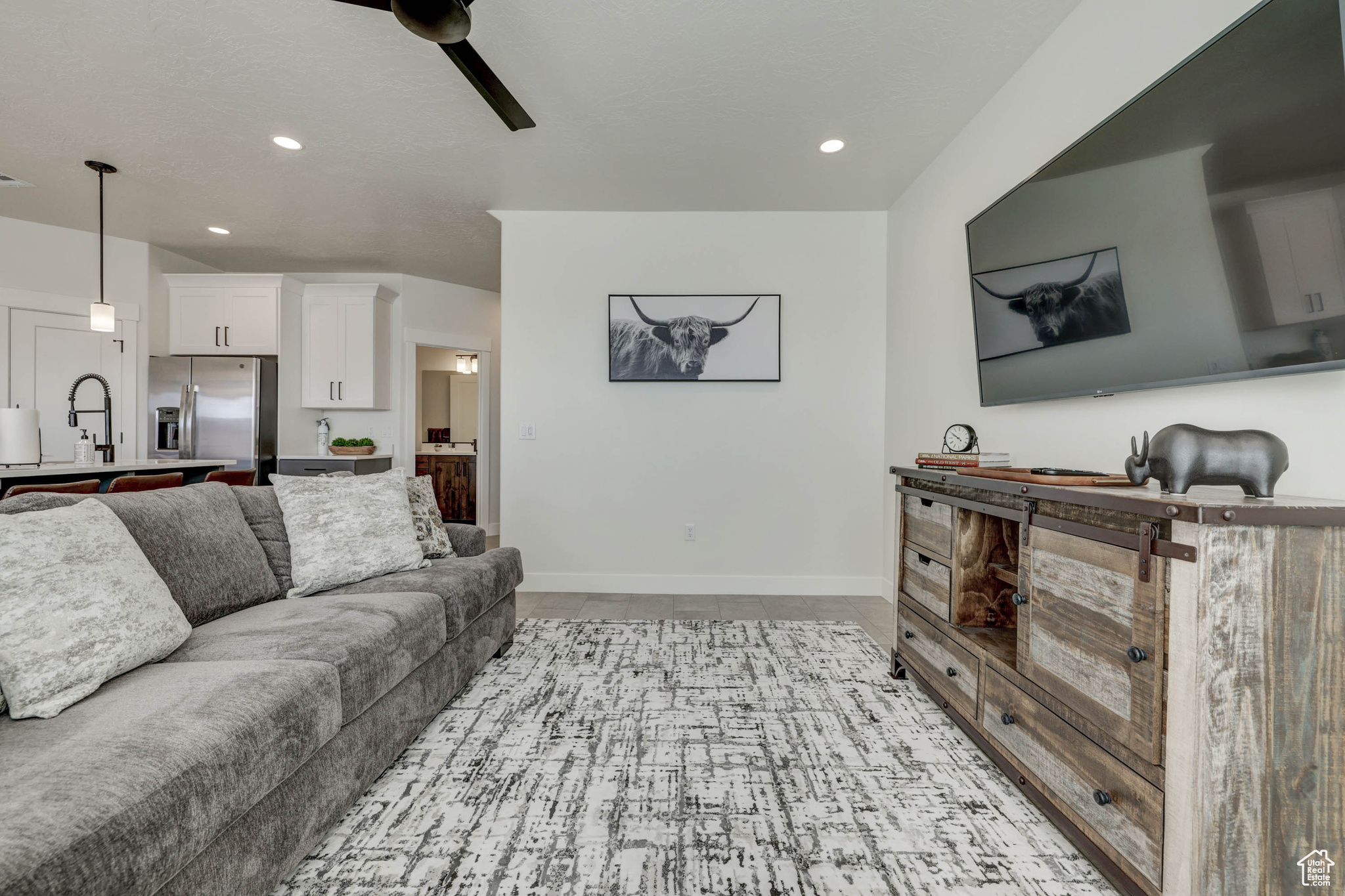 Living room featuring light tile floors, ceiling fan, and sink