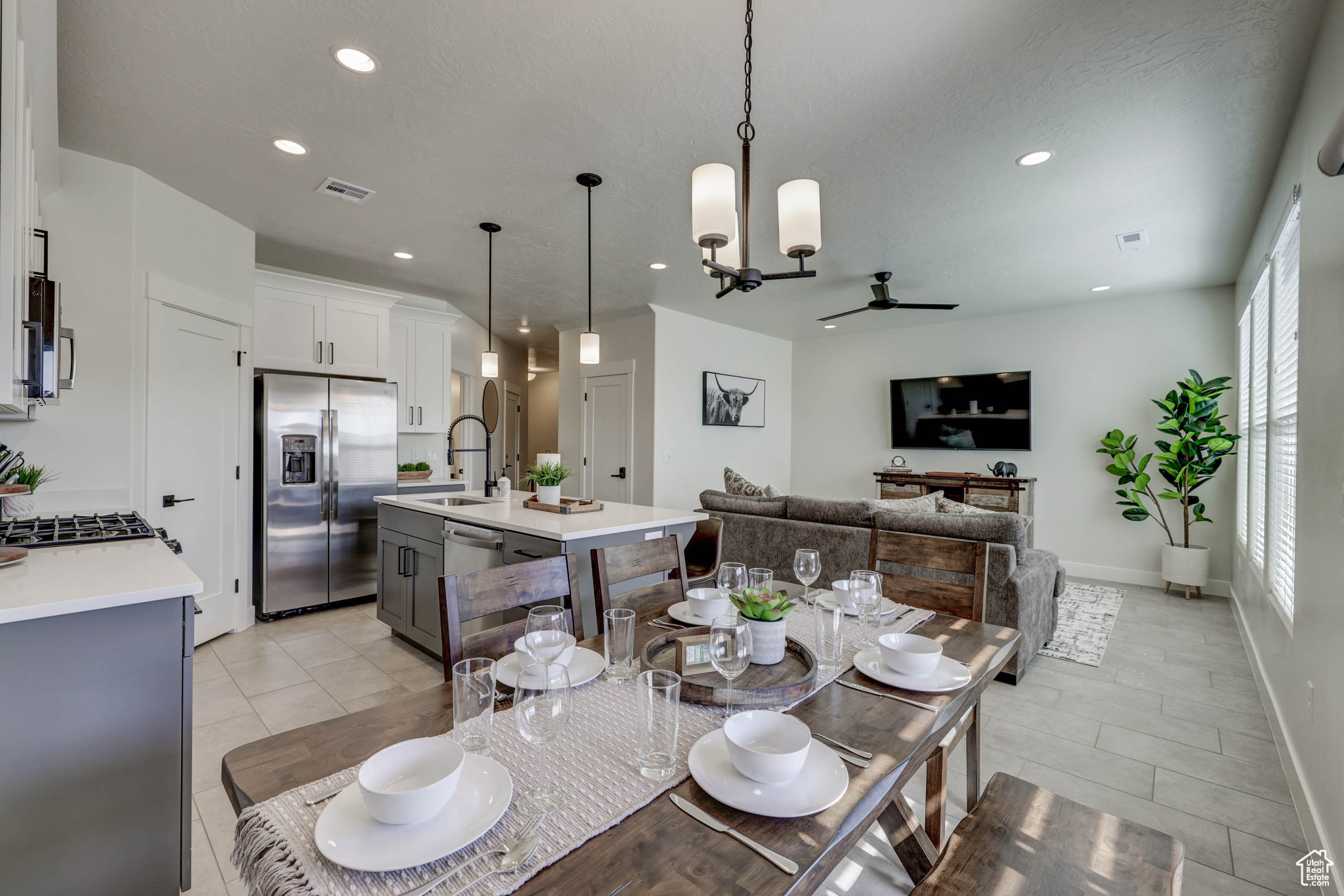 Tiled dining space featuring sink and ceiling fan with notable chandelier