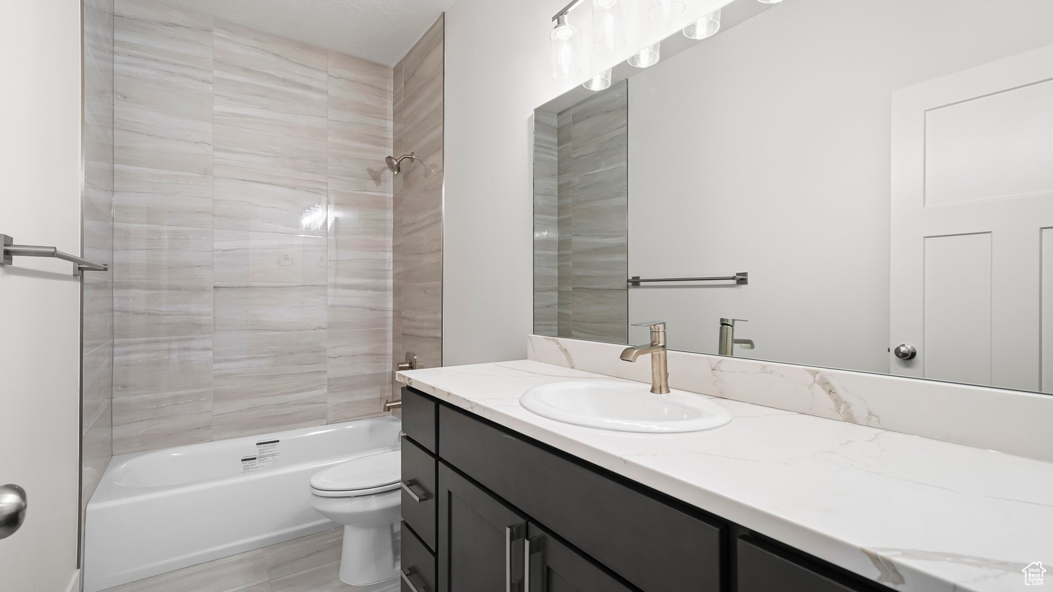 Full bathroom with toilet, tiled shower / bath combo, and large vanity