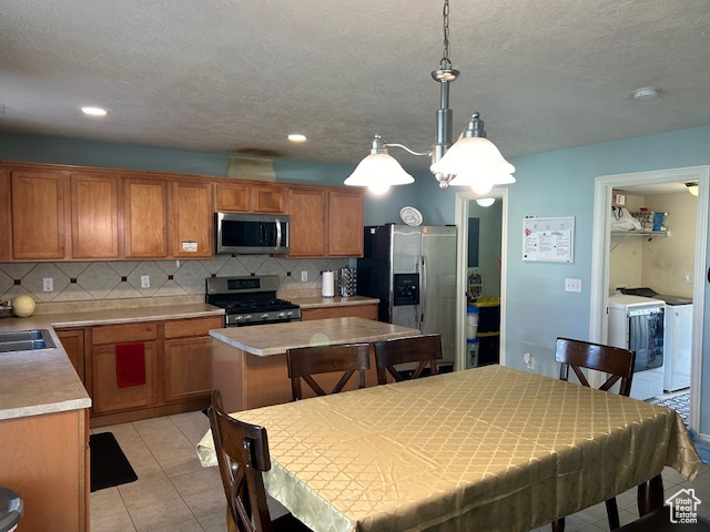 Kitchen with appliances with stainless steel finishes, independent washer and dryer, tasteful backsplash, and pendant lighting