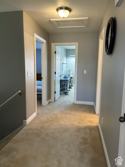 Corridor with light colored carpet and a textured ceiling