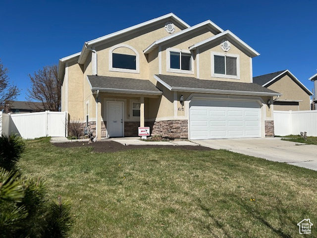 View of front of property with a garage and a front lawn