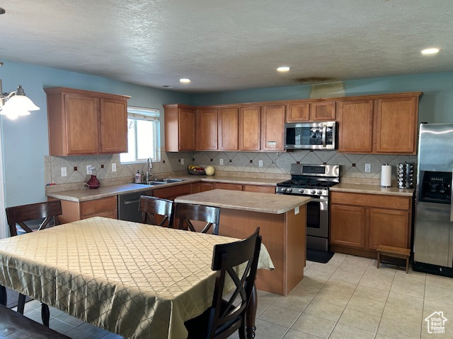 Kitchen with stainless steel appliances, light tile floors, sink, a kitchen island, and tasteful backsplash