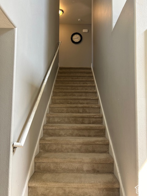 Stairway featuring dark carpet