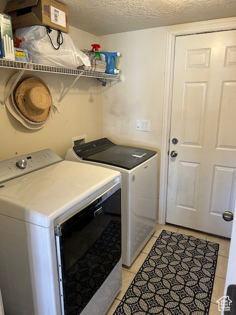 Laundry area featuring a textured ceiling, hookup for a washing machine, independent washer and dryer, and light tile flooring