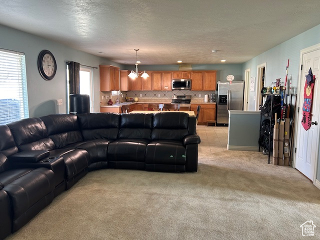 Family room featuring a healthy amount of sunlight, sink, a notable chandelier, and light carpet