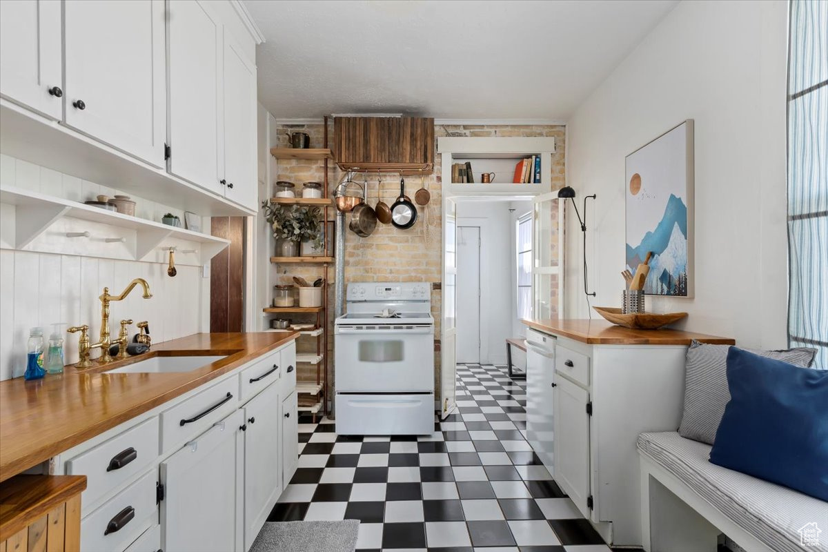 Kitchen featuring dark tile floors, white cabinets, white appliances, backsplash, and sink