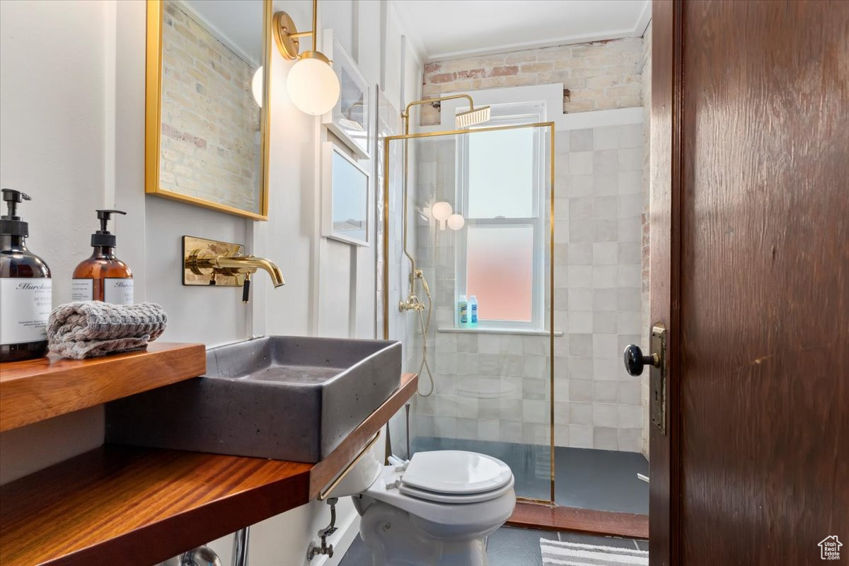Bathroom featuring a shower with shower door, toilet, and ornamental molding