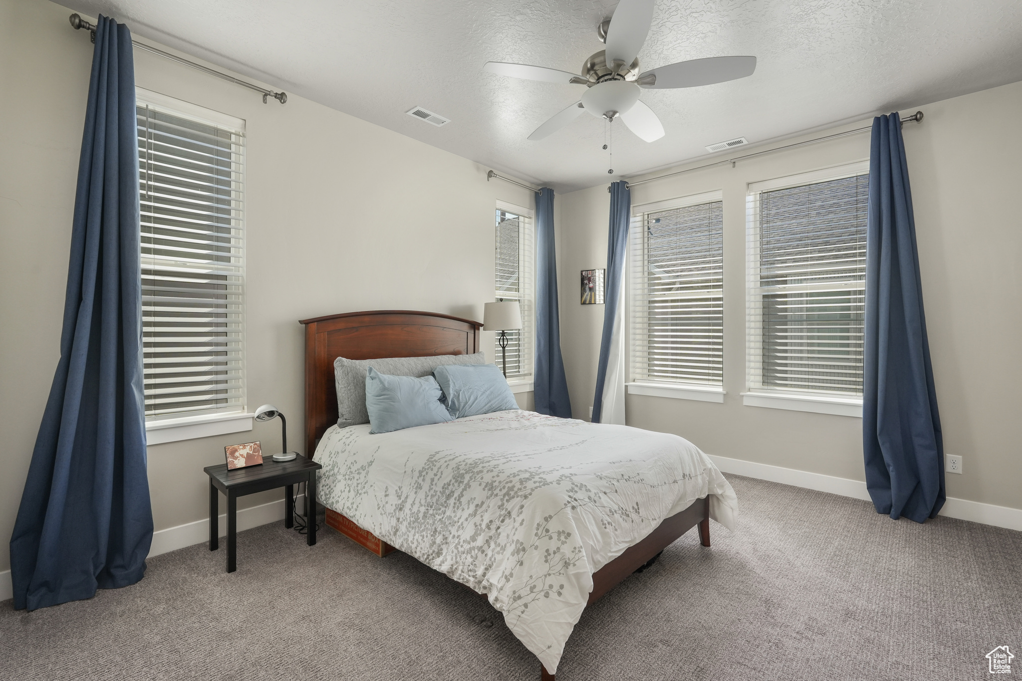 Master bedroom with large windows and ceiling fan