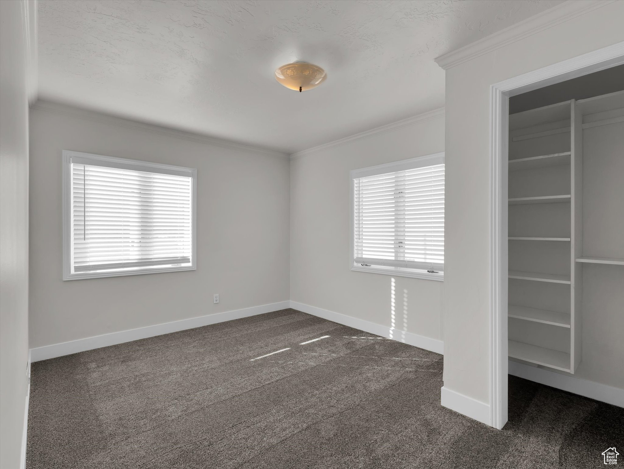 Unfurnished bedroom with ornamental molding and dark carpet