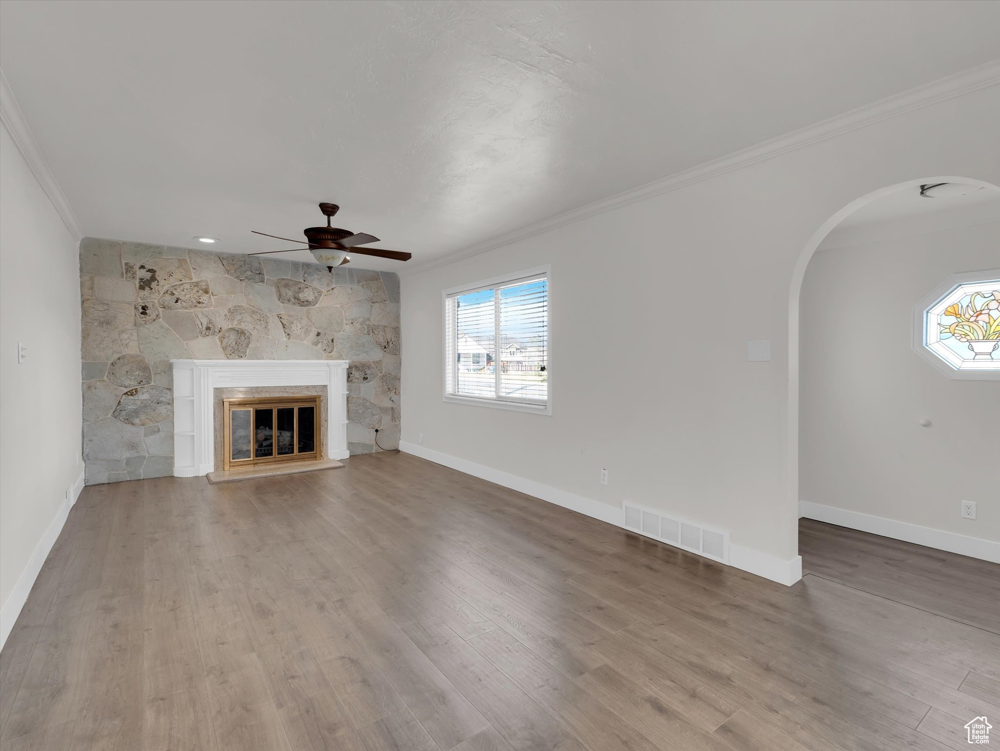 Unfurnished living room featuring ceiling fan, ornamental molding, and hardwood / wood-style flooring
