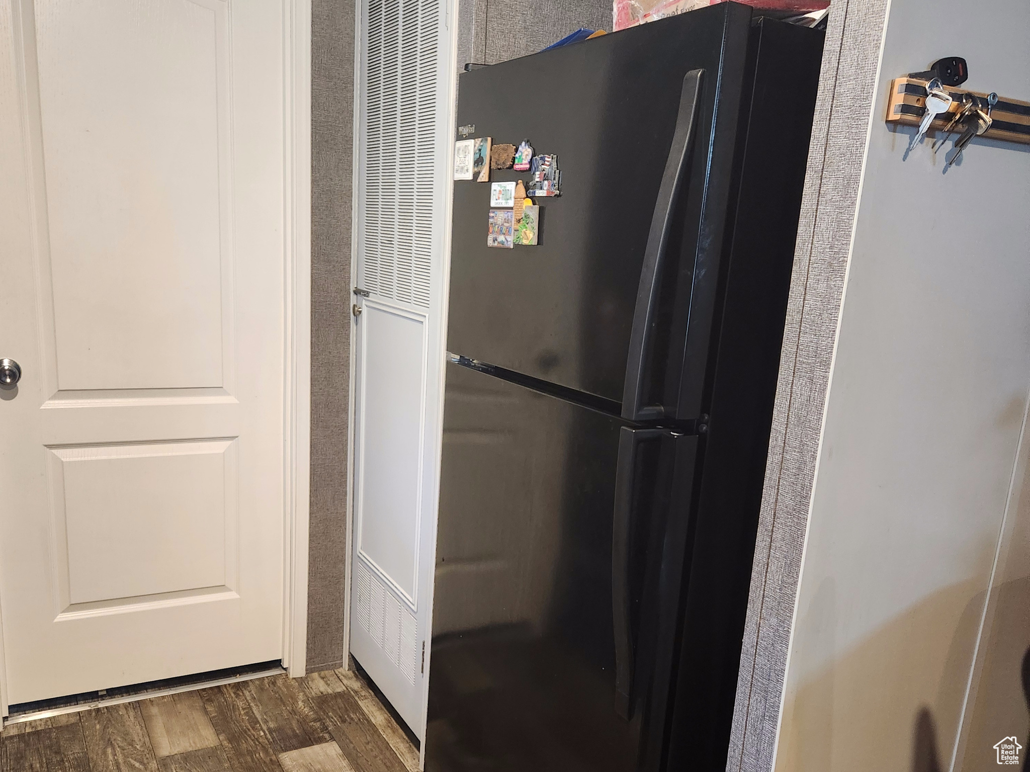 Kitchen with black refrigerator and dark wood-type flooring