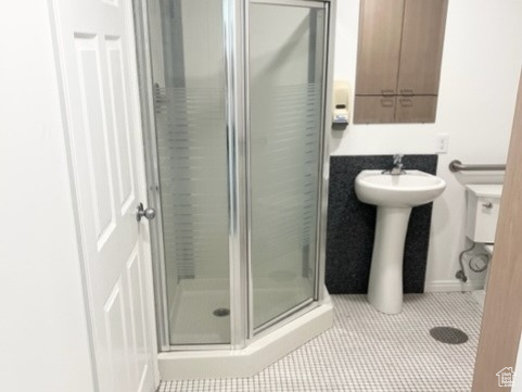 Bathroom featuring tile flooring, sink, and a shower with door