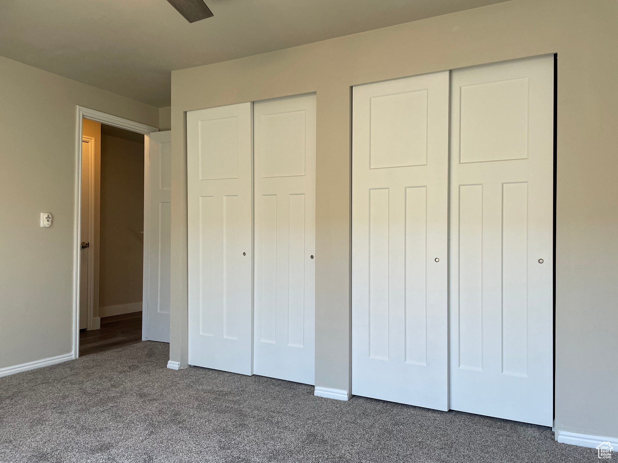Unfurnished bedroom with multiple closets, dark colored carpet, and ceiling fan