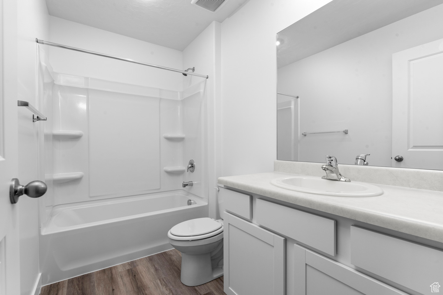Full bathroom with wood-type flooring, vanity, shower / bathtub combination, and toilet