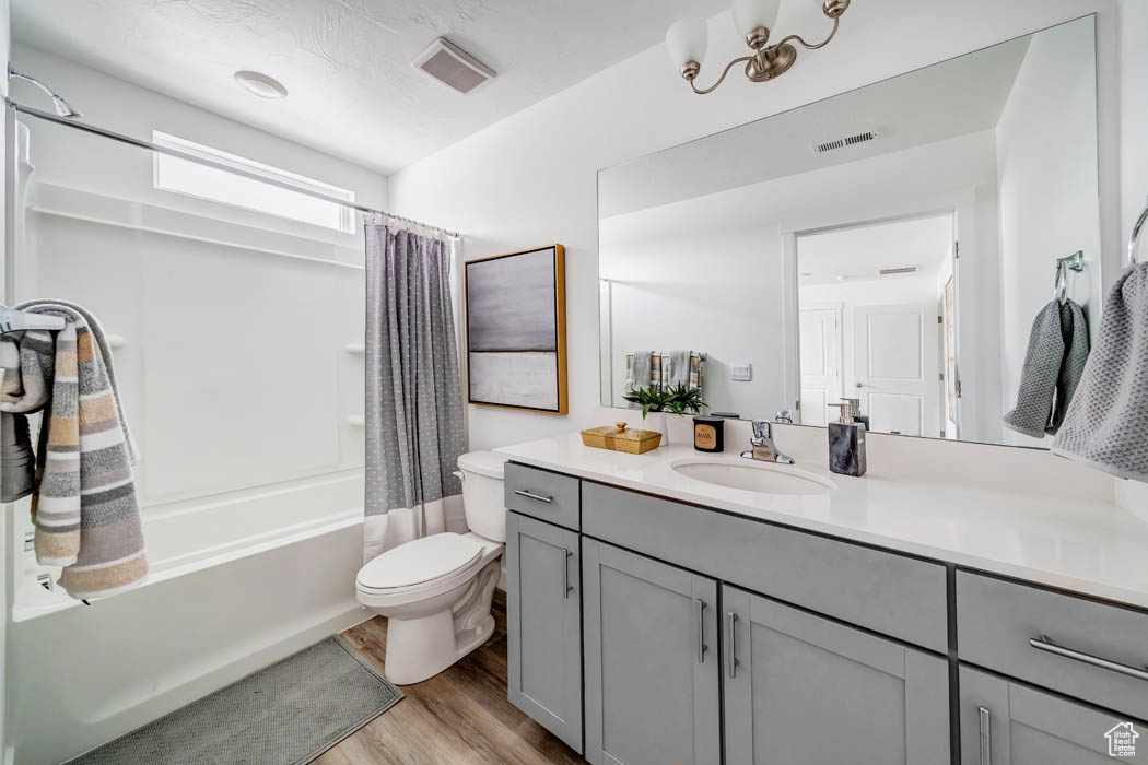 Full bathroom with hardwood / wood-style floors, vanity, toilet, and shower / bath combo with shower curtain