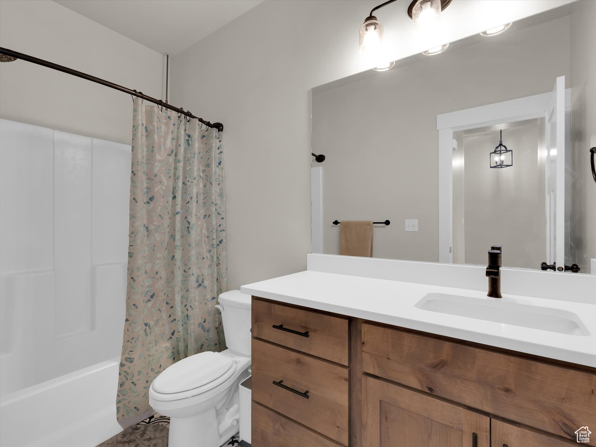 Full bathroom with toilet, large vanity, and shower / bath combo with shower curtain