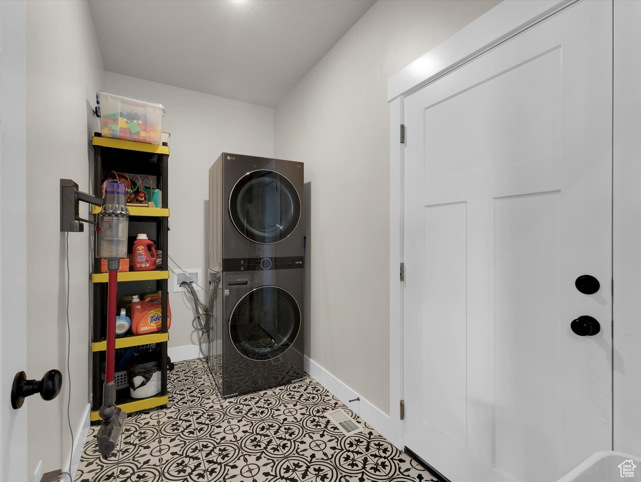 Laundry room with stacked washer / drying machine and light tile flooring