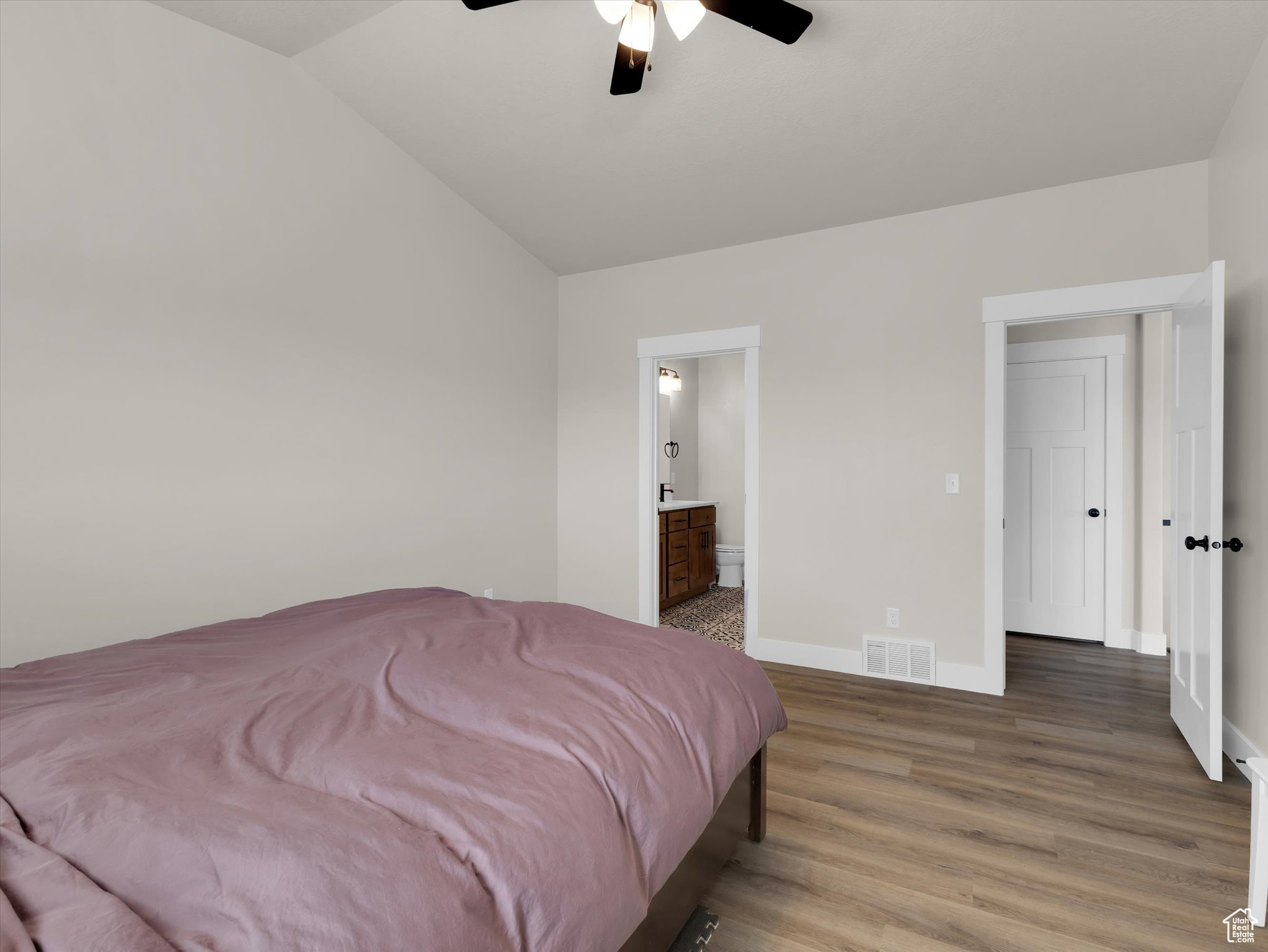 Bedroom with connected bathroom, vaulted ceiling, ceiling fan, and dark hardwood / wood-style flooring