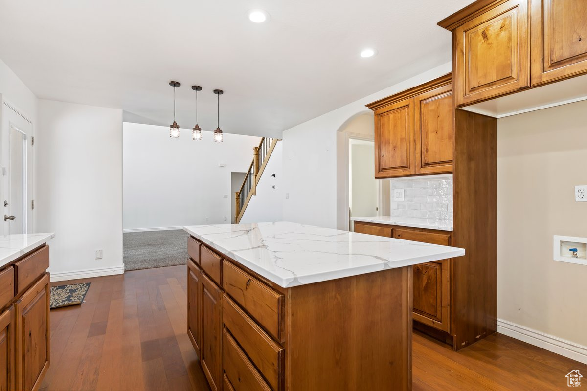 Kitchen featuring hanging light fixtures, backsplash, hardwood / wood-style flooring, and a kitchen island