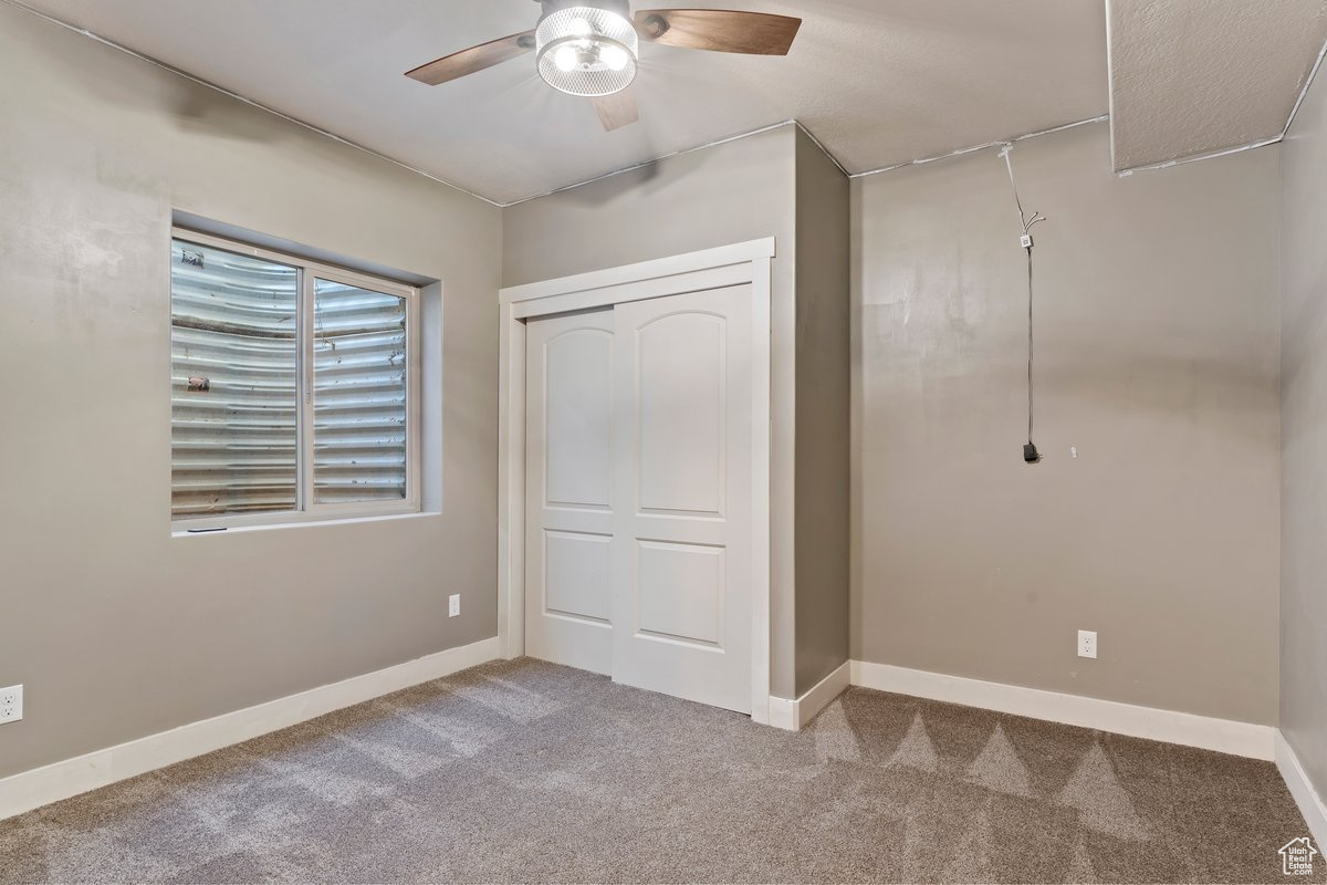 Unfurnished bedroom featuring light carpet, a closet, and ceiling fan