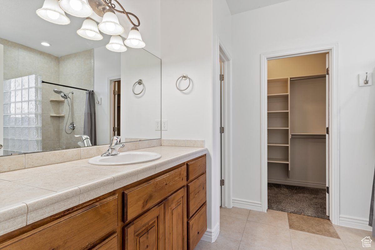 Double sink, Bathroom with tile flooring, large vanity, and a tile shower