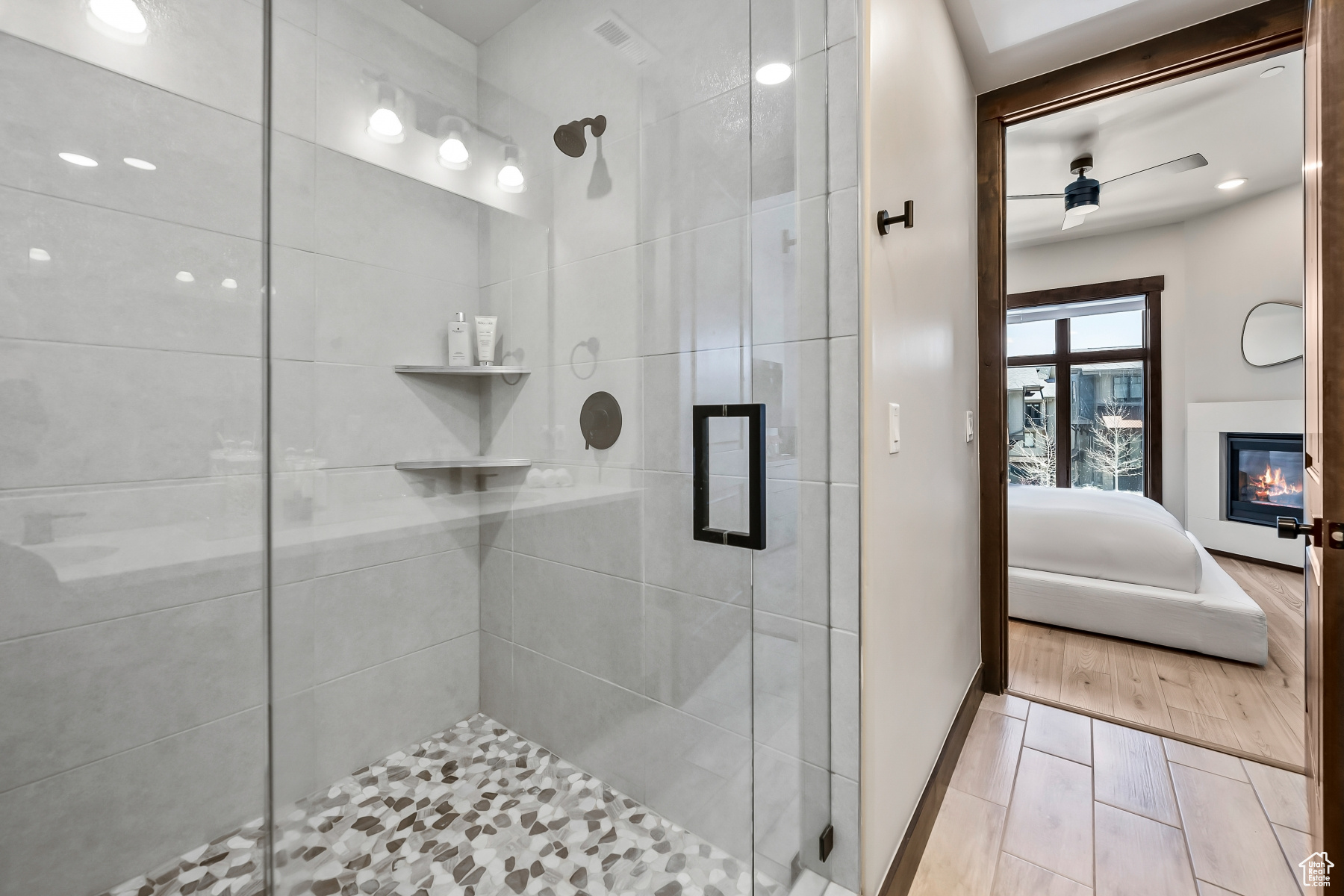 Bathroom featuring ceiling fan, an enclosed shower, and hardwood / wood-style flooring