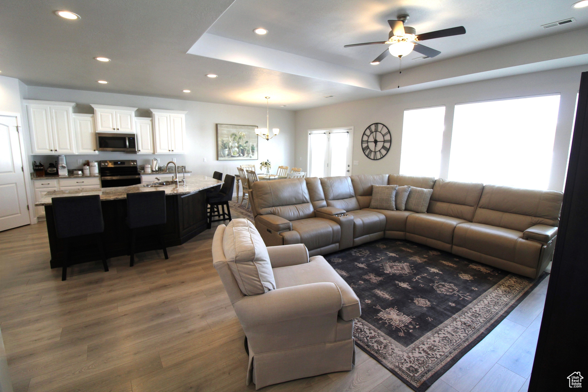 Living room featuring ceiling fan with notable chandelier, dark hardwood / wood-style floors, a raised ceiling, and sink