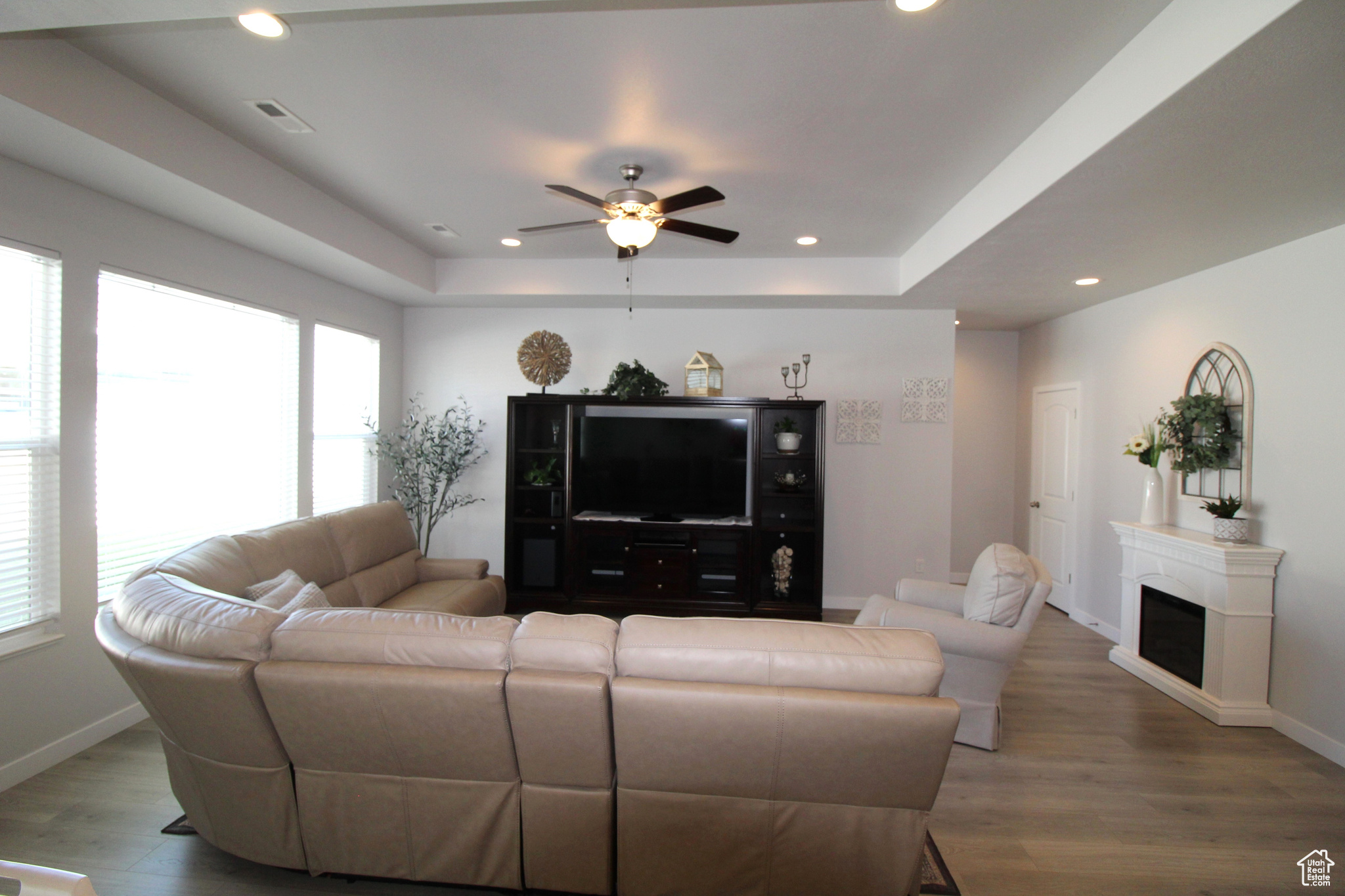 Living room with ceiling fan, a tray ceiling, and hardwood / wood-style flooring