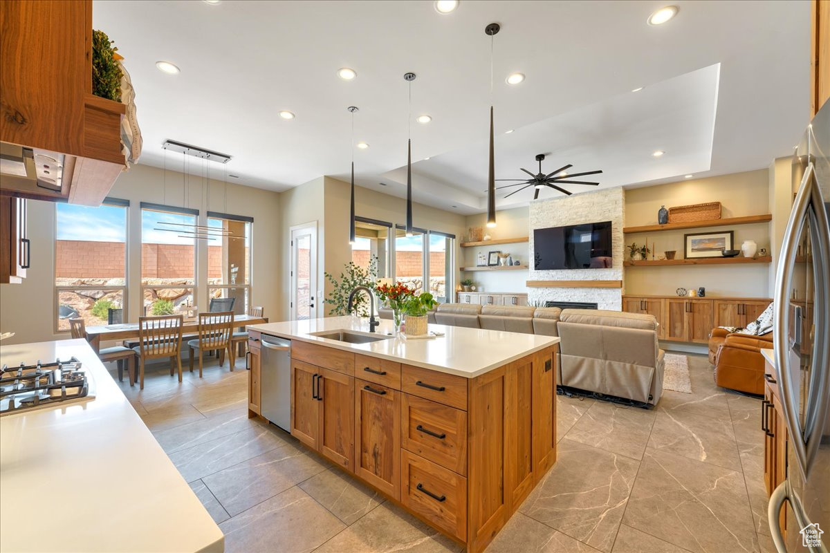 Kitchen featuring appliances with stainless steel finishes, ceiling fan, a fireplace, sink, and pendant lighting
