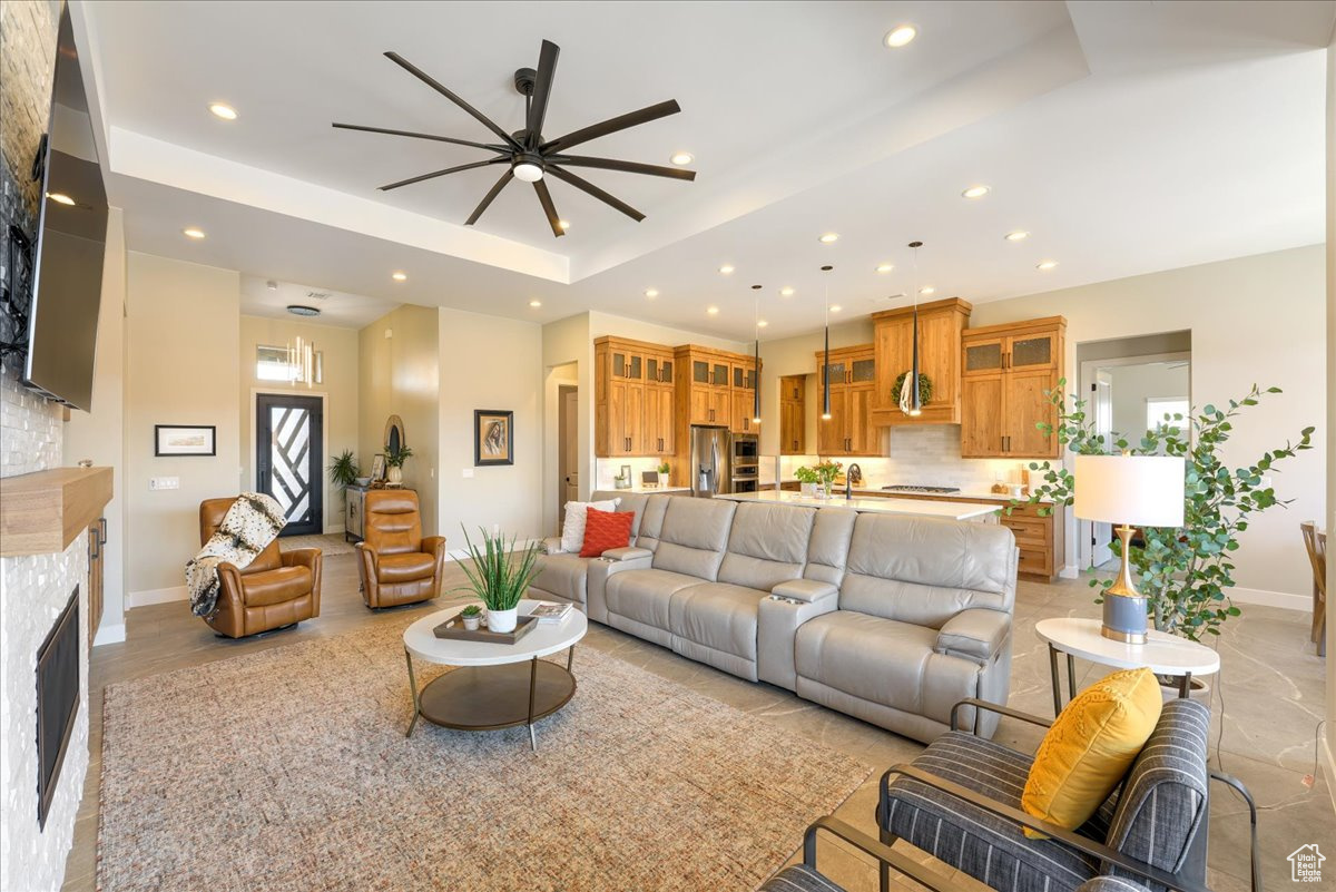 Living room with a raised ceiling, ceiling fan, and sink