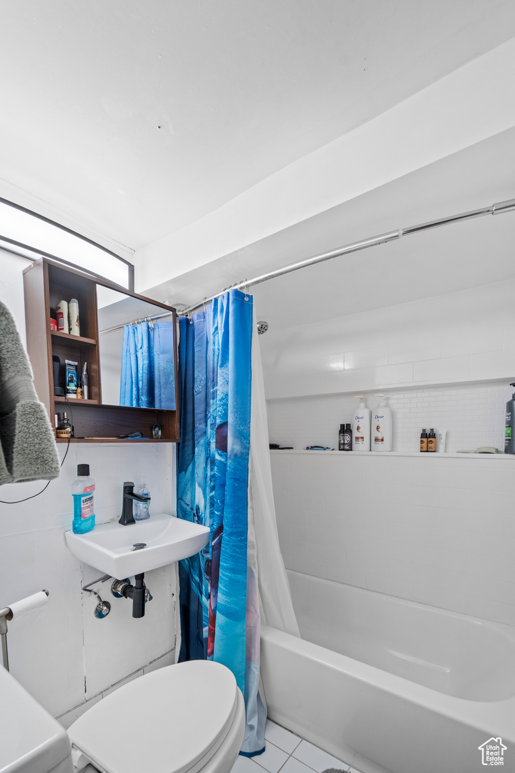 Bathroom with tile floors, shower / bath combination with curtain, and toilet
