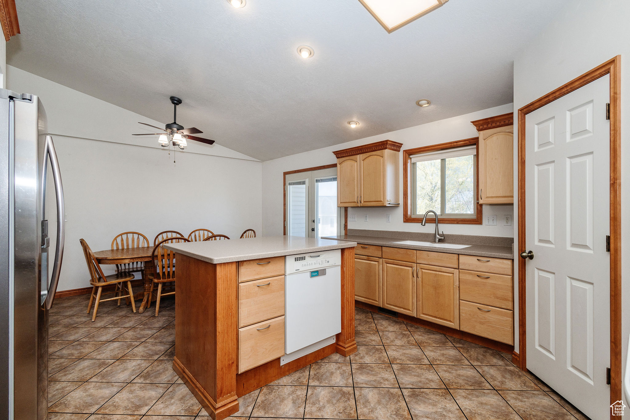 Kitchen with ceiling fan, light tile floors, dishwasher, stainless steel fridge with ice dispenser, and vaulted ceiling