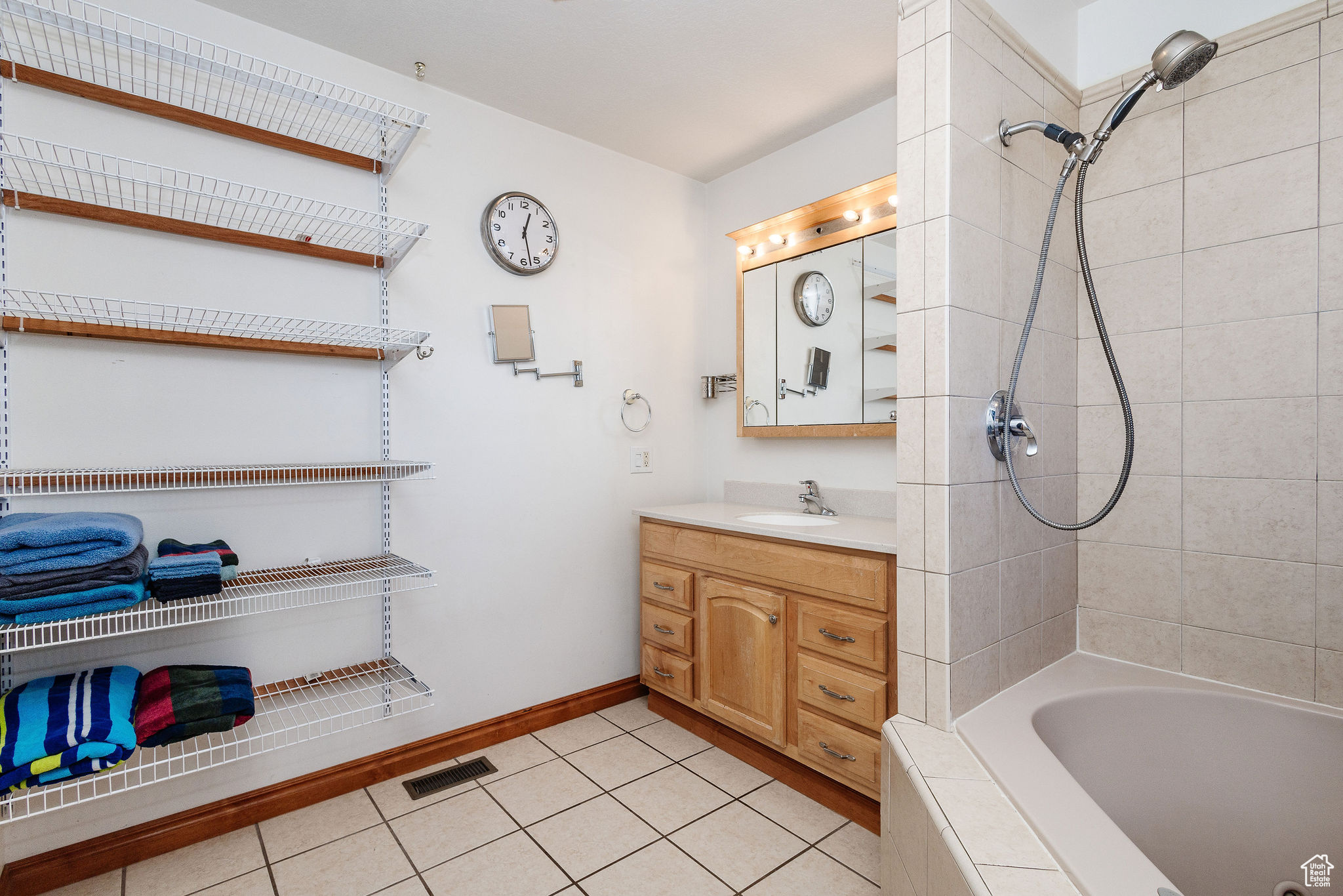 Bathroom featuring tiled shower / bath combo, tile floors, and vanity with extensive cabinet space