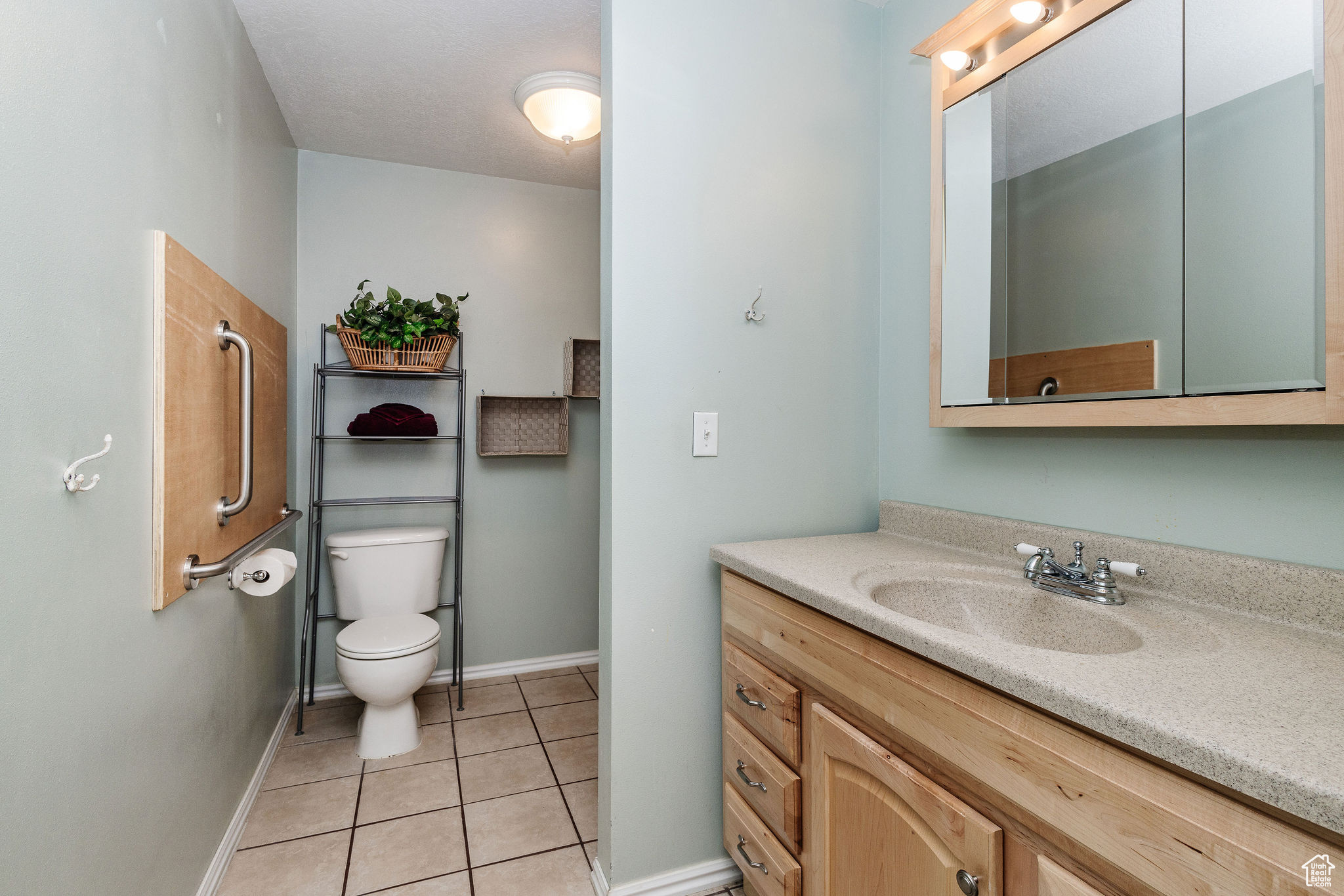 Bathroom with tile floors, toilet, and large corian vanity with solid surface sink.