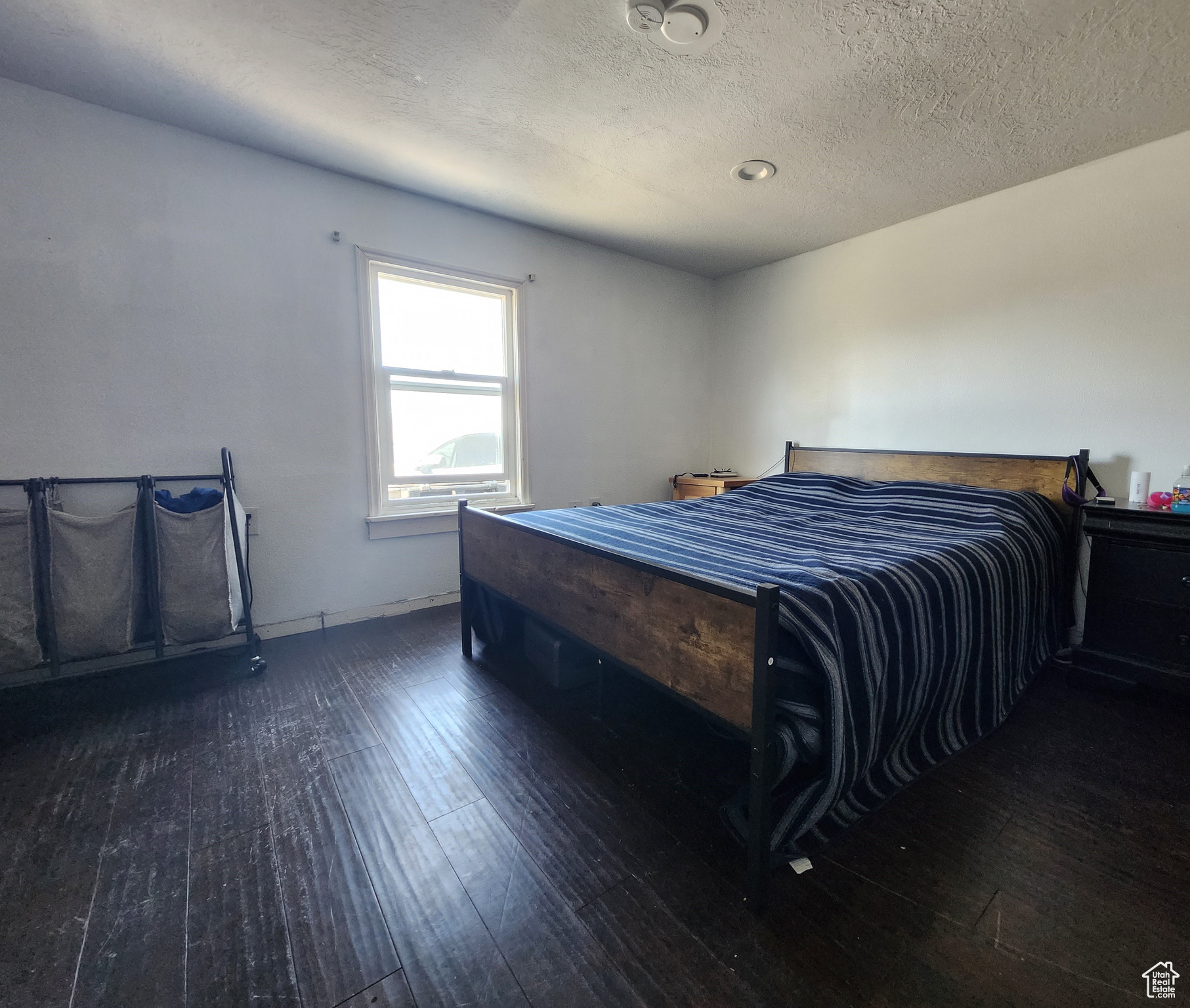 Bedroom with a textured ceiling and dark hardwood / wood-style flooring