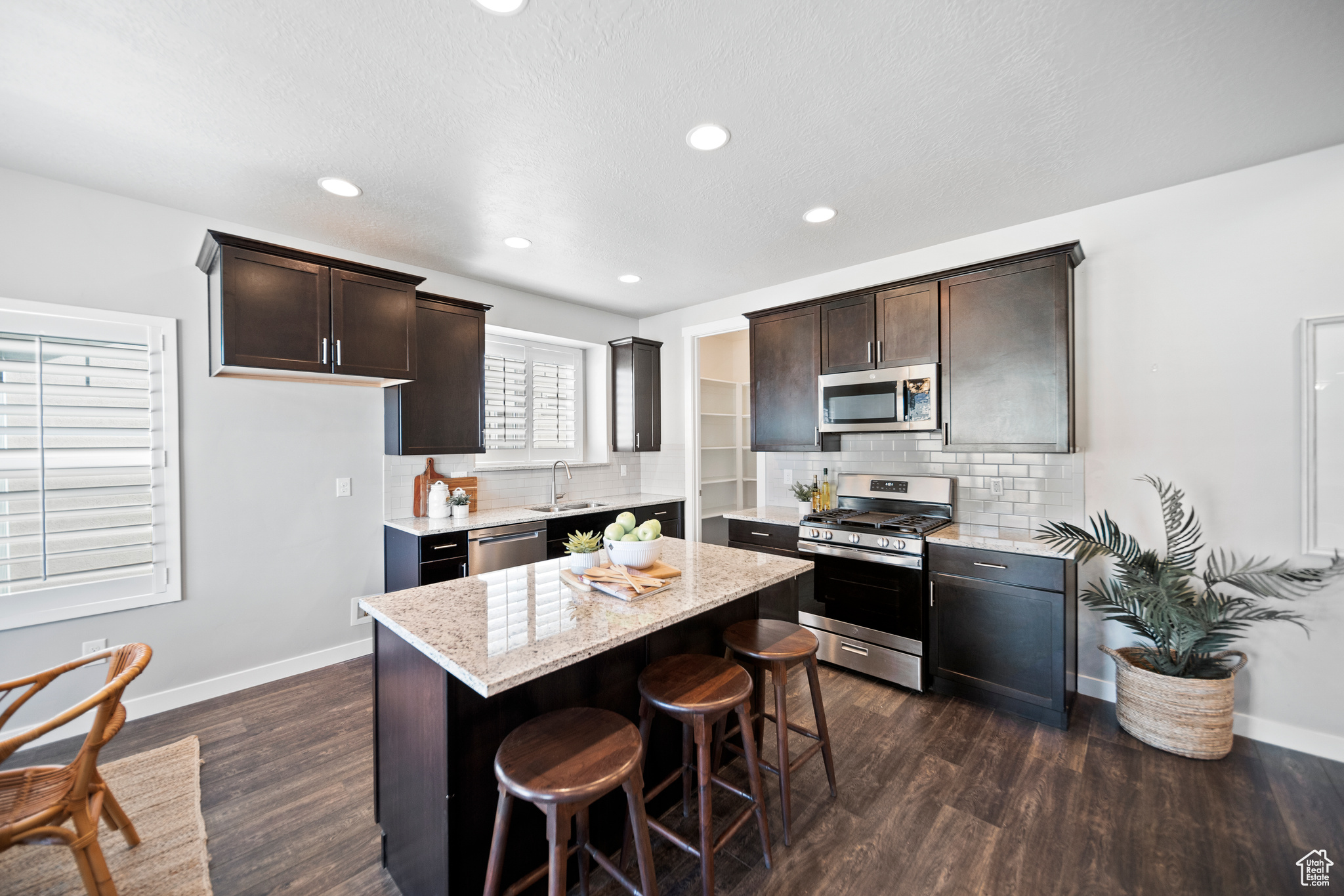 Kitchen featuring a center island, backsplash, a breakfast bar area, dark wood-type flooring, and stainless steel appliances
