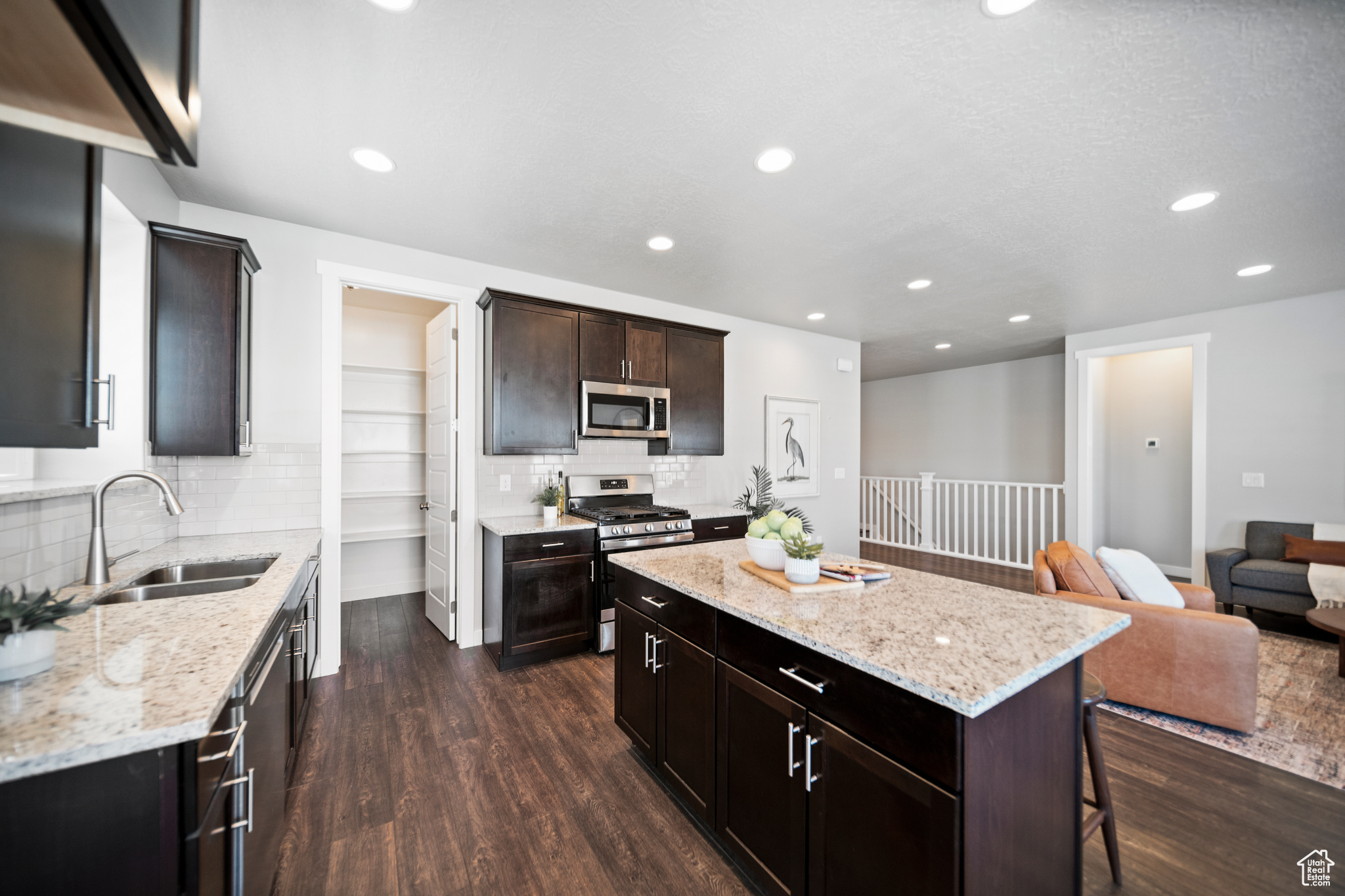 Kitchen featuring a breakfast bar, dark hardwood / wood-style floors, stainless steel appliances, sink, and tasteful backsplash