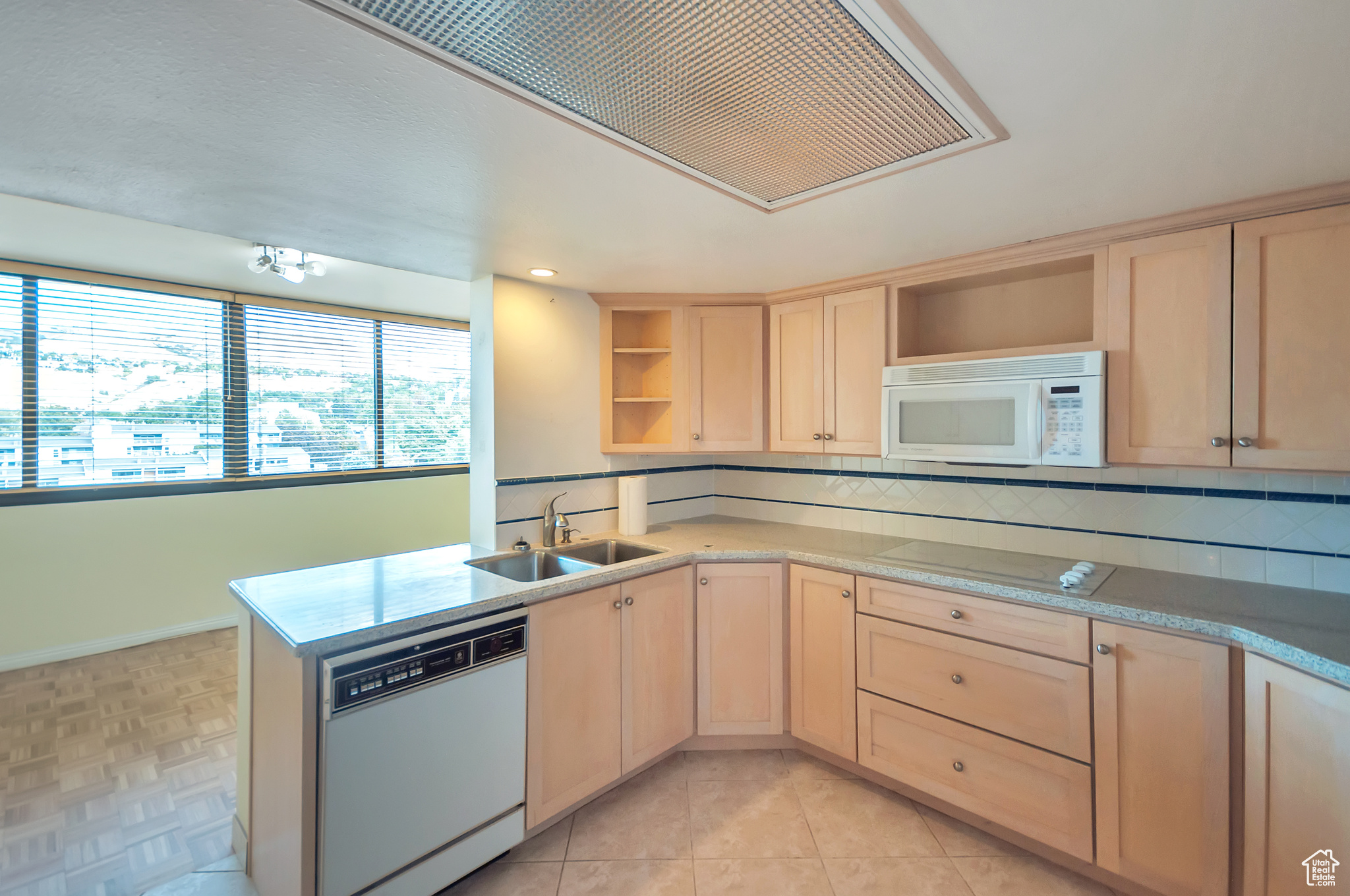 Kitchen with light brown cabinets, white appliances, tasteful backsplash, and sink